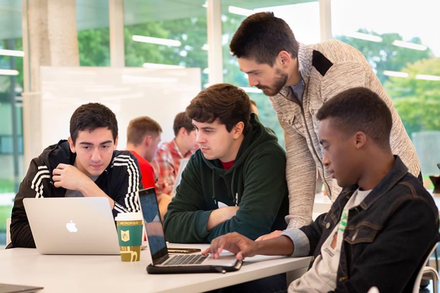 Students working together in an IPRO class around a laptop