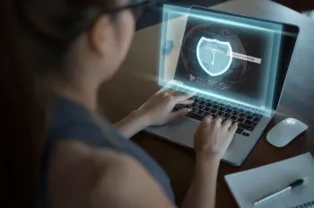 a person typing on a laptop that has a screen of cyber badge in blue