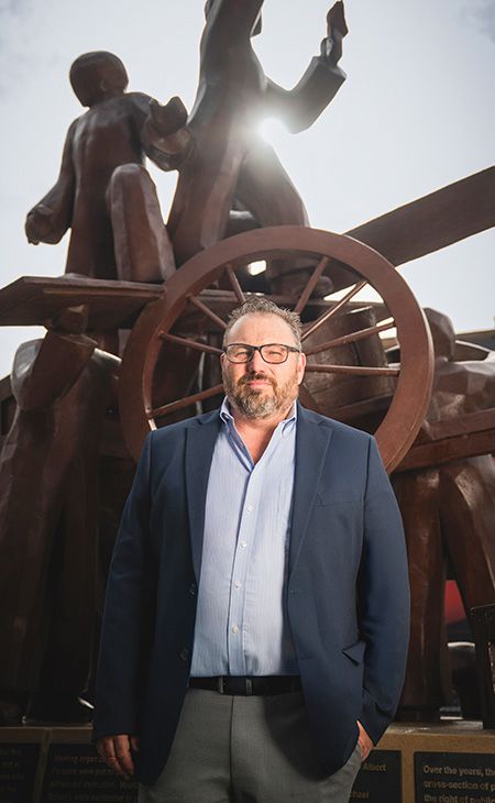 Bob Reiter (LAW ’03) sits in front of the Haymarket Memorial—a sculpture that symbolizes the labor groups involved in the Haymarket affair of 1889—located in Chicago’s Fulton River District.
