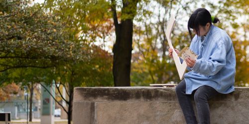 A student working outside on main campus on a class project