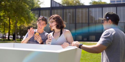 three students discussing a project in front of crown hall