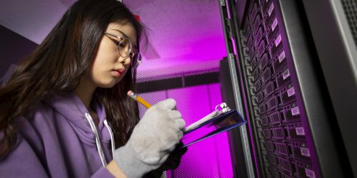 Female student takes notes on computer servers