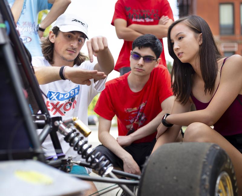 A member of the IIT motorsports club explains mechanics to two students